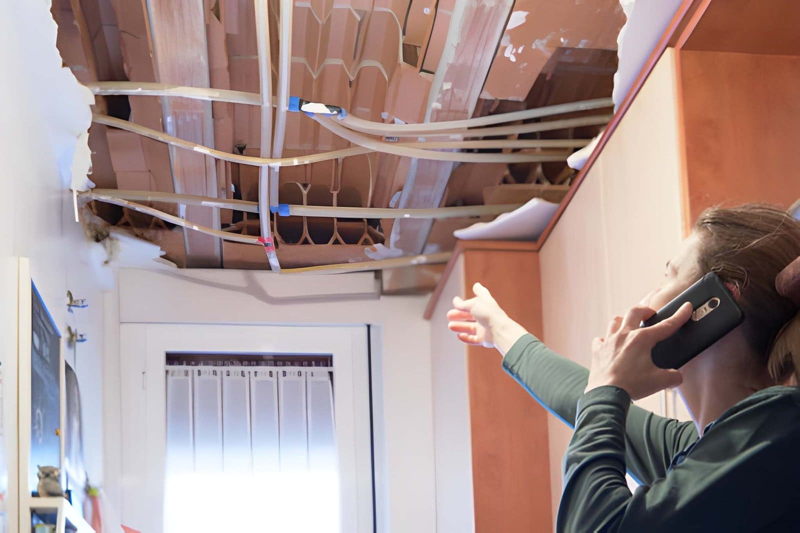 Home Watch Jensen Beach inspector assessing severe ceiling damage with exposed beams and pipes.